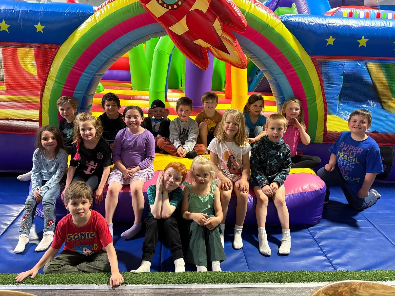 A group of kids smiling on colorful inflatables at the Field House